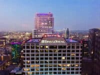 Modern city skyline featuring the Ernst & Young headquarters building illuminated at dusk, with surrounding skyscrapers and vibrant city lights emphasizing urban business district prominence.